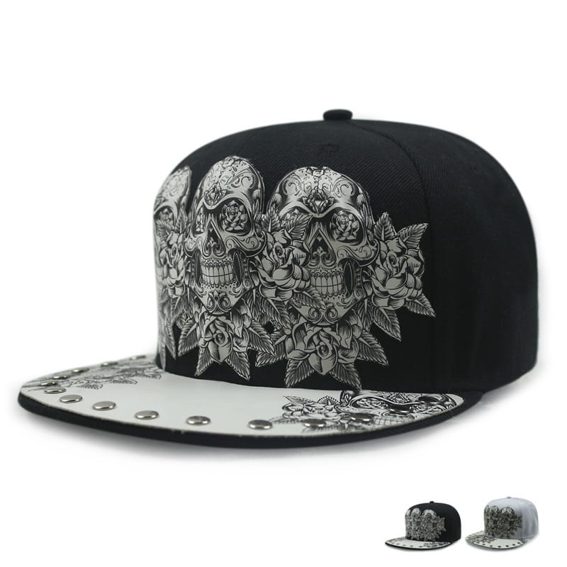 Black snapback baseball cap featuring intricate silver sugar skull and rose designs with a white brim adorned by metallic studs in the sugar skull rivet snapback baseball cap style.