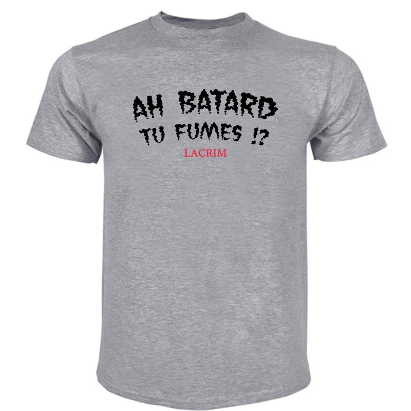 T-shirt en coton pour homme, motif graphique, manches courtes, couleur gris chiné, présentant un texte imprimé noir et rouge bien visible « ah batard tu fumes » avec « lacrim » en lettres rouges plus petites en dessous.