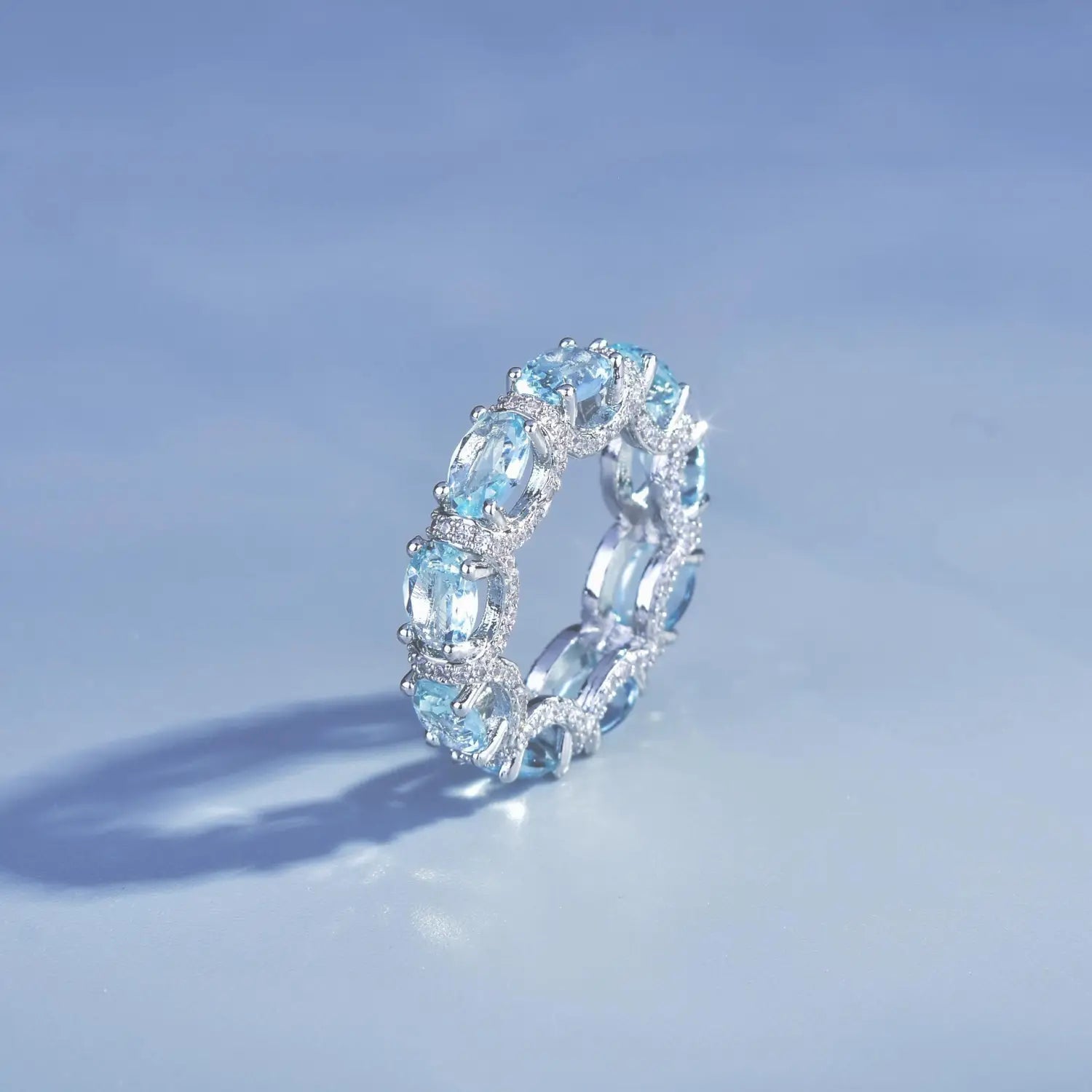 Elegant silver band ring from the aquamarine crystal bridal jewelry set featuring a continuous row of oval-cut sky blue topaz stones accented with sparkling diamonds.