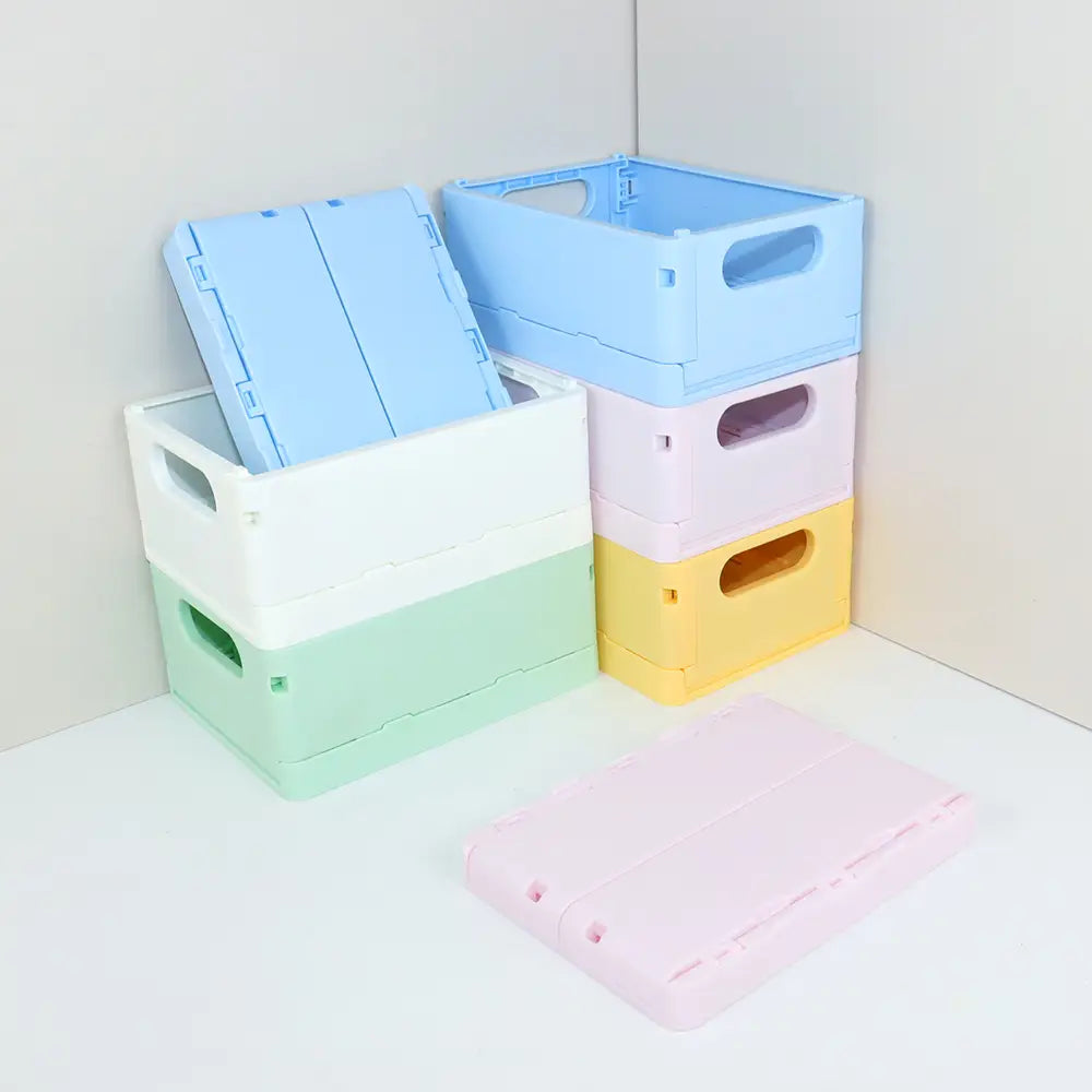 pastellfarbene faltbare Kunststoff-Aufbewahrungsboxen in hellblau, weiß, mintgrün und gelb mit integrierten Griffen, ausgelegt als Falt-Aufbewahrungsboxen-Körbchen für die Organisation am Desktop.