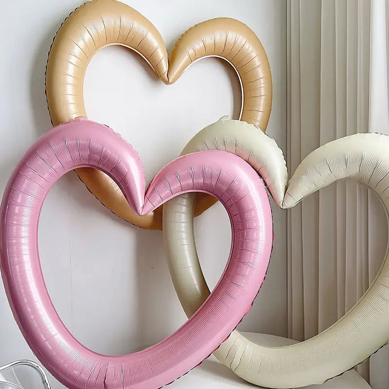 Decoración de fiesta con marco de foto de globo que presenta globos tipo lámina con forma de corazón en color rosa dorado y crema, con acabado metálico brillante.
