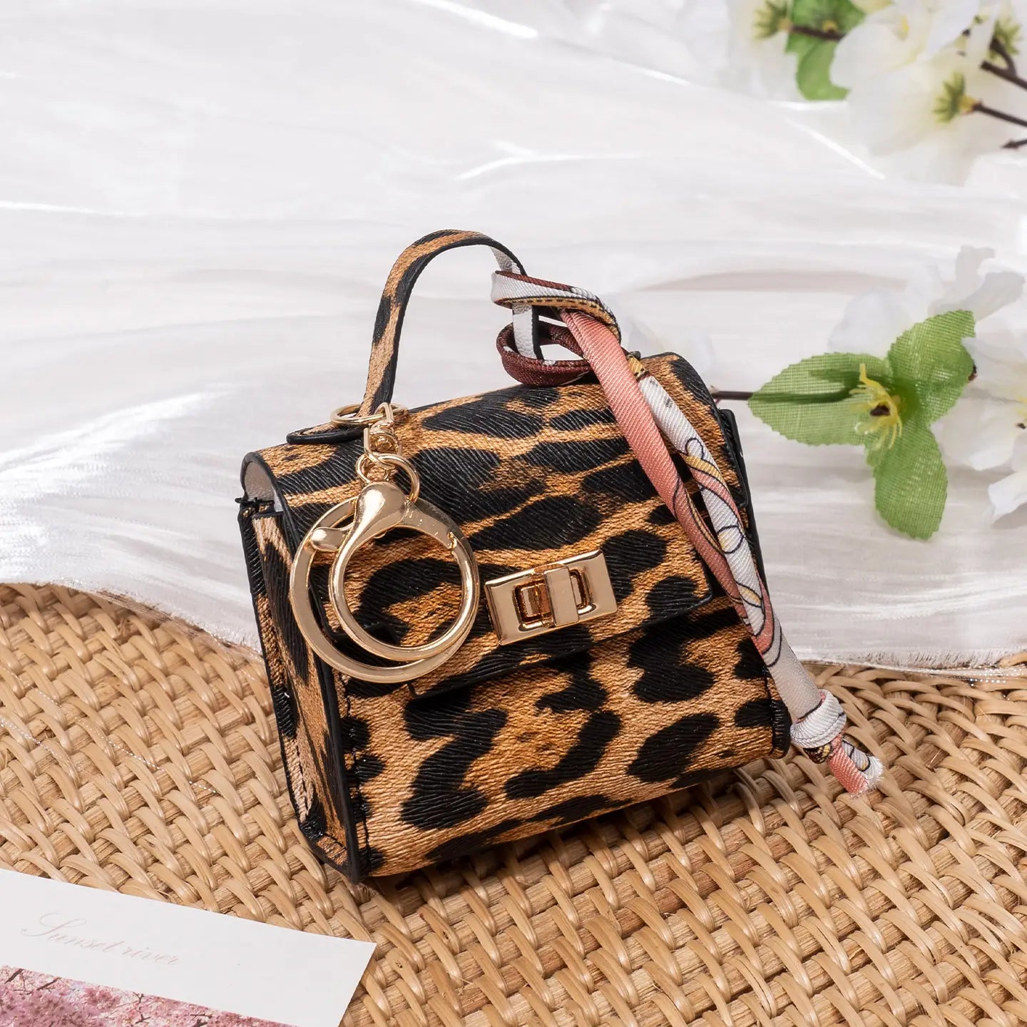 Miniature handbag keychain with leopard print, gold-tone hardware, and matching silk scarf accessory.