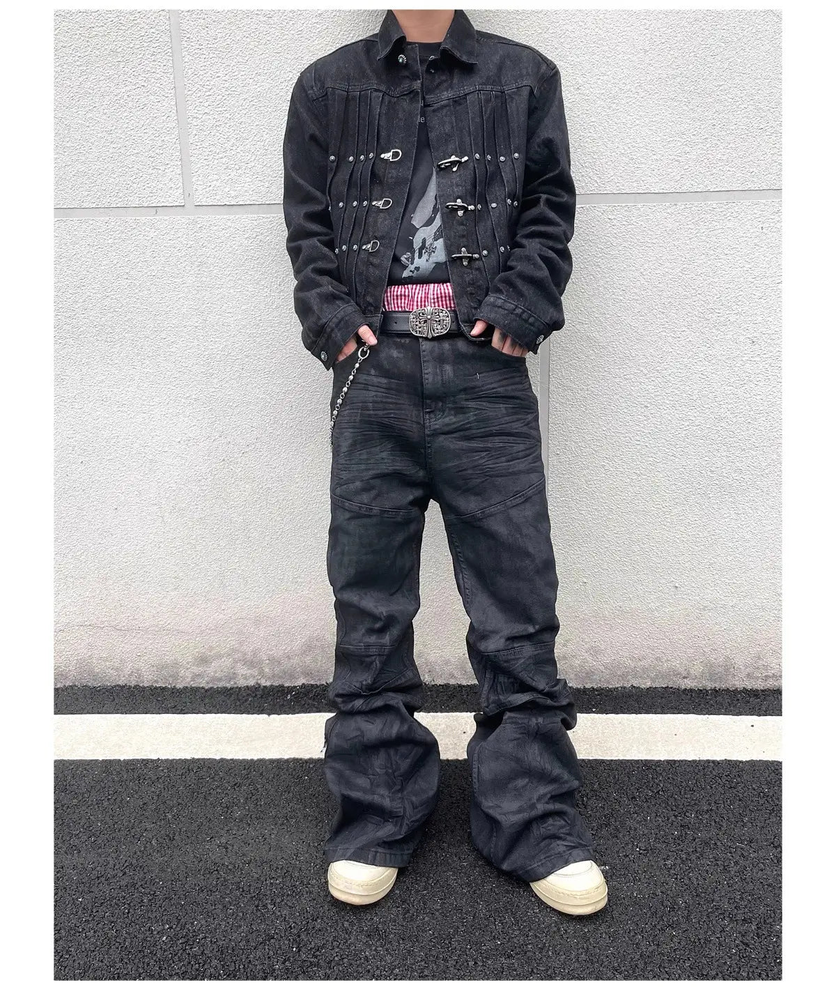 Une veste en denim noire avec quincaillerie métallique à tons argentés et des boutons décoratifs associée à des jeans empilés en denim noir Y2k vintage pour hommes.