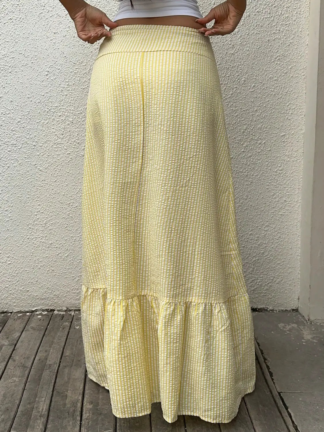 Maxi-jupe jaune pâle à motifs rayés subtils et ourlet froncé, dans un tissu léger, idéale pour une tenue décontractée ou pour l’été.