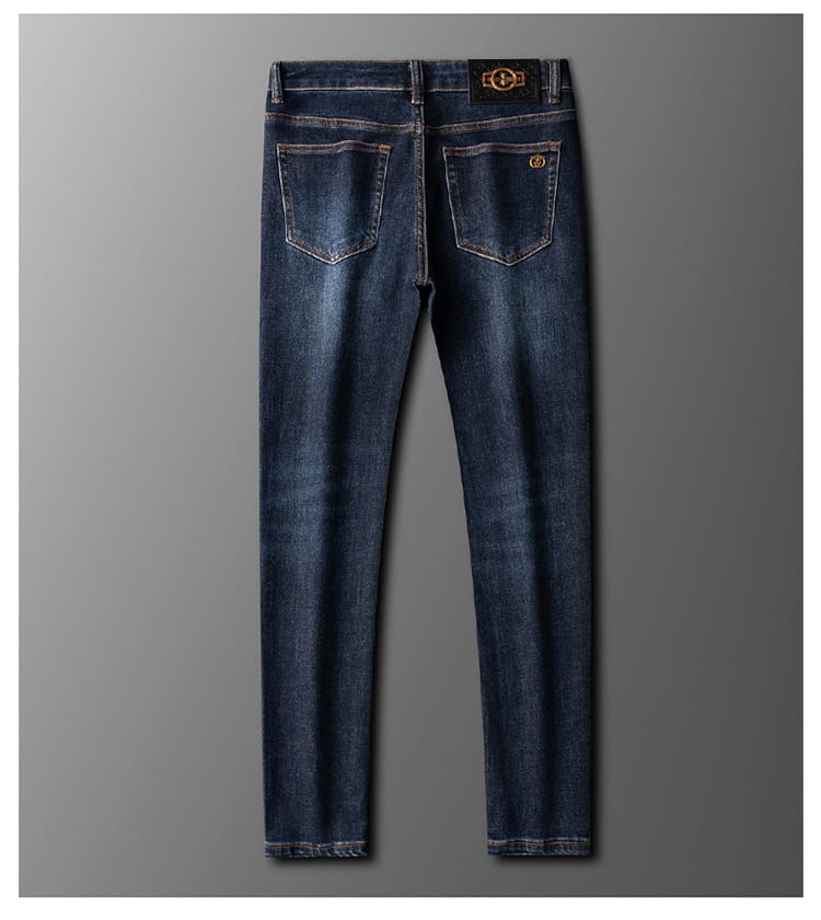 Slim fit dark blue denim jeans for men with subtle fading and gold tone branding on the back waistband and rear pockets shown from the back side.