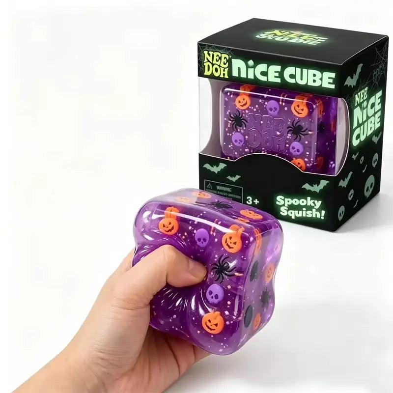cube halloween violet needoh tout doux d’agitation sensorielle, présentant des jack-o’-lanternes oranges, des crânes violets et des araignées noires intégrés dans un matériau translucide à l’aspect gel, en tant que jouet d’agitation sensorielle tout doux.