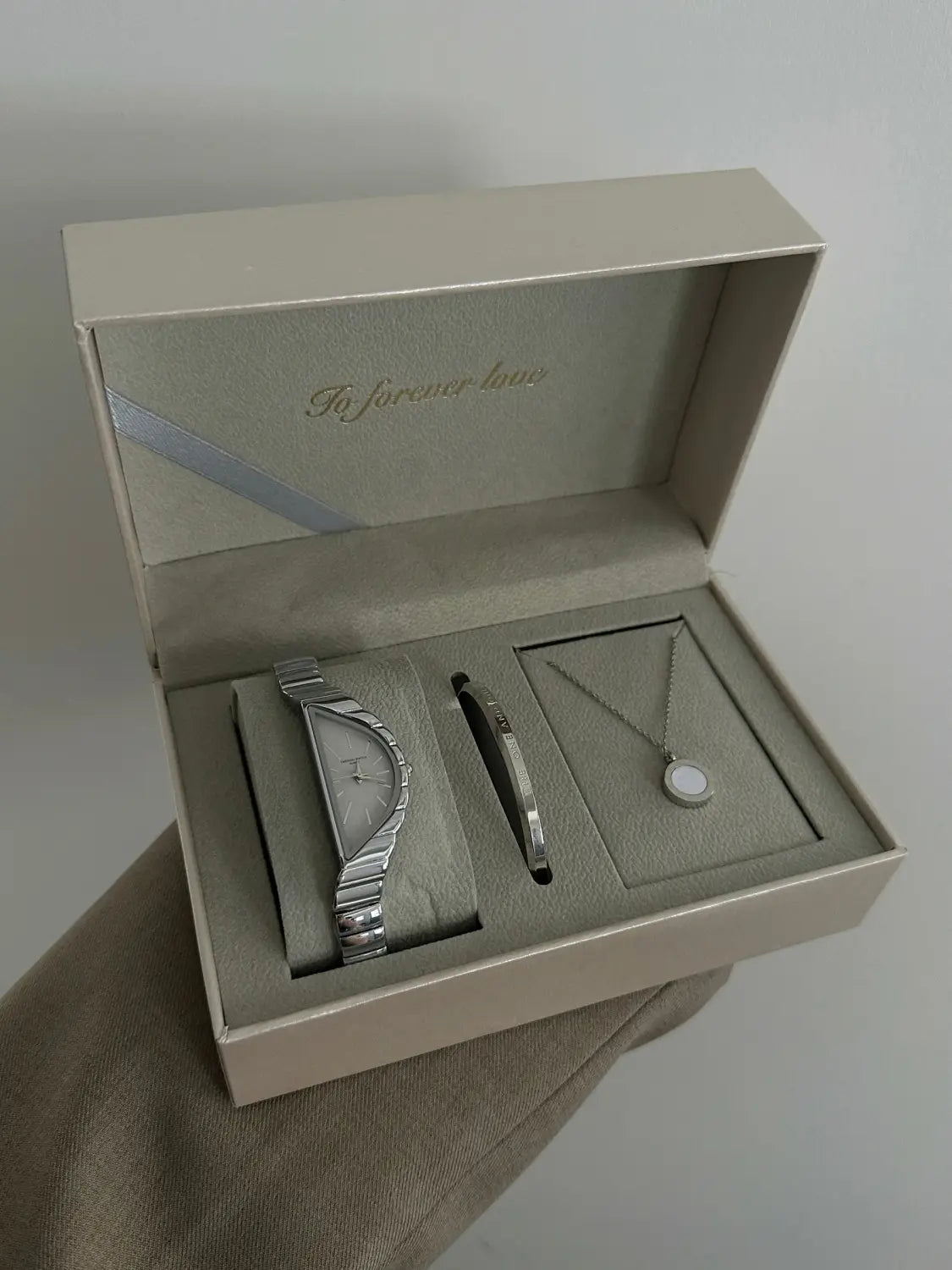 Silver-toned geometric triangle quartz watch with a textured stainless steel segmented band and minimalist dial in an elegant gift box.