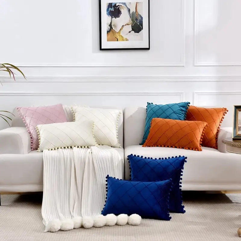 ensemble de housses de coussin matelassées colorées, comprenant une housse de coussin en velours gris avec pompons, suscitant des retours positifs pour son garnissage duveteux et une variété de couleurs, notamment rose, blanc, bleu canard, orange et bleu marine