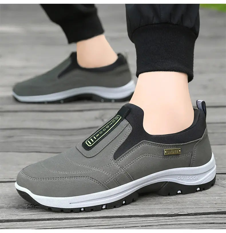 Men orthopedic slip-on walking shoe in gray and black with a white midsole and velcro strap detail designed for outdoor use.