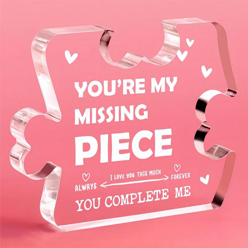 Plaque-souvenir en acrylique translucide rose représentant un couple de pièces de puzzle, avec un texte blanc gravé et des motifs de cœurs.