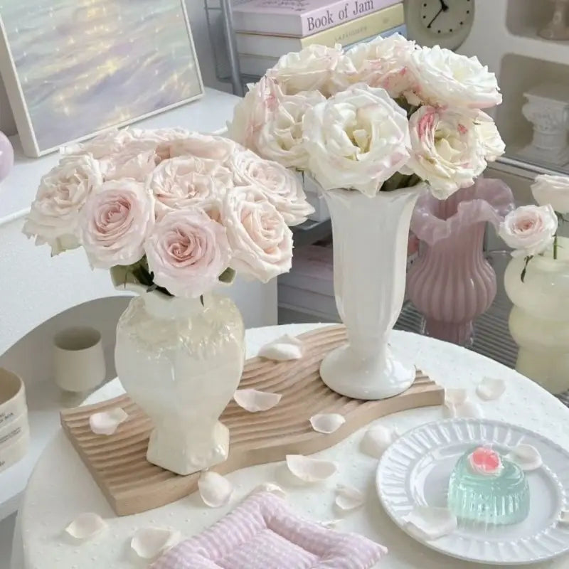 Jarrones de cerámica modernos franceses elegantes en color blanco con delicados patrones florales que sostienen arreglos exuberantes de rosas suaves rosadas y blancas cremosas para una decoración sofisticada del hogar.