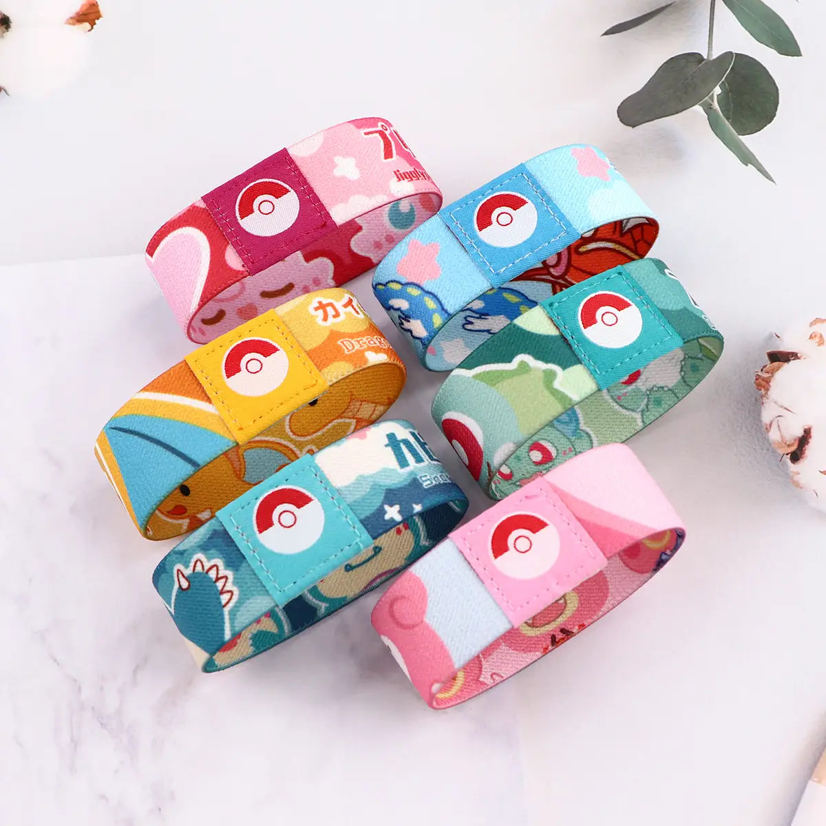 Colorful stretch wristband bracelets made of fabric featuring Pokémon cartoon designs with a central red and white Poké Ball logo on each.