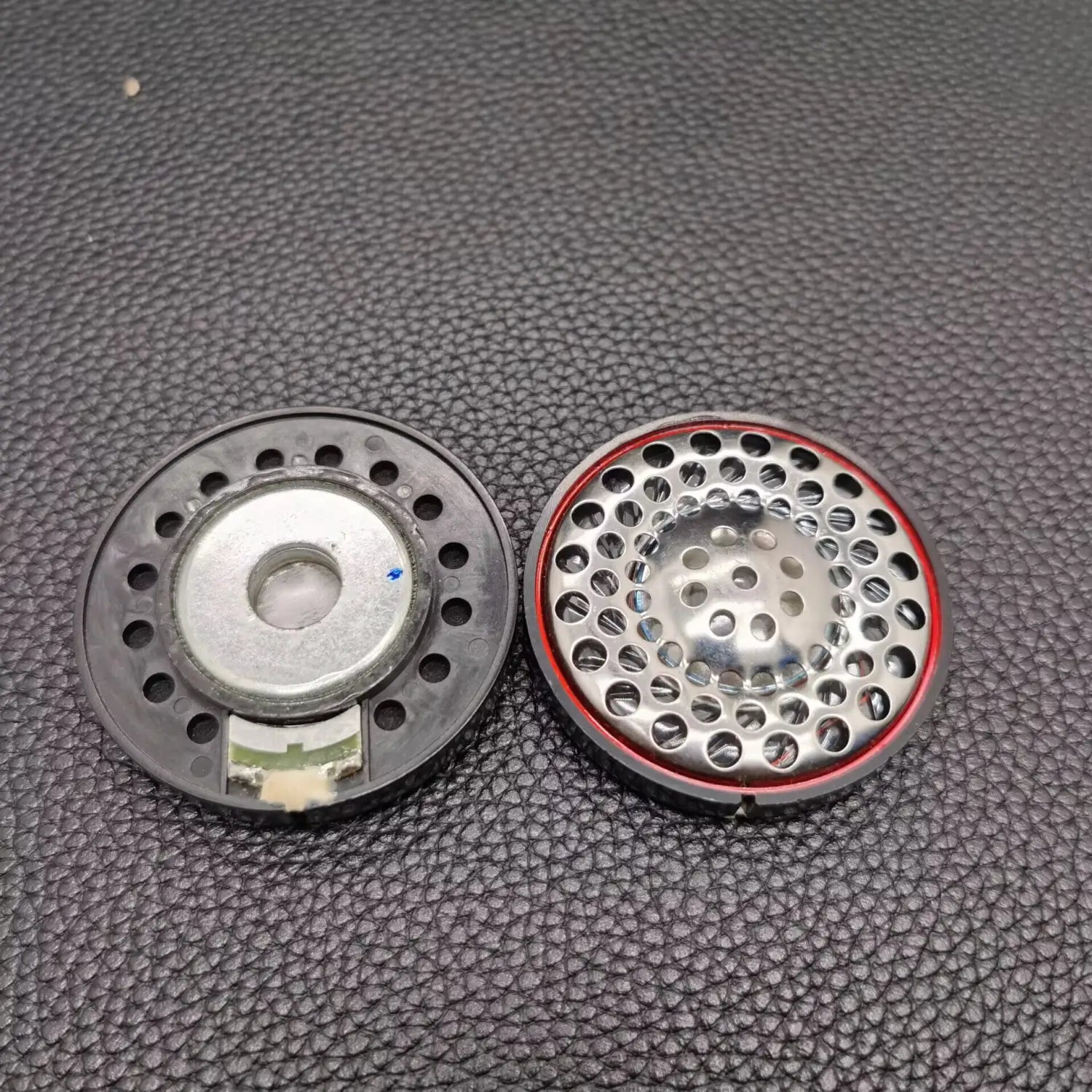 dos altavoces de repuesto para auriculares Ath-ad900x, uno con carcasa de plástico negro y centro de metal plateado y el otro con rejilla metálica perforada y ribete rojo