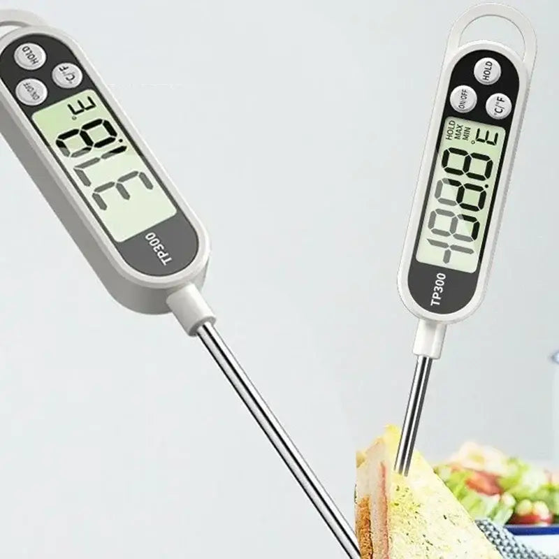 Weißes digitales Fleischthermometer mit Edelstahlfühler und schwarzen Bedientasten, das Temperaturanzeigen in einem digitalen Fleischthermometer für die Sofortanzeige von Lebensmitteln zeigt.