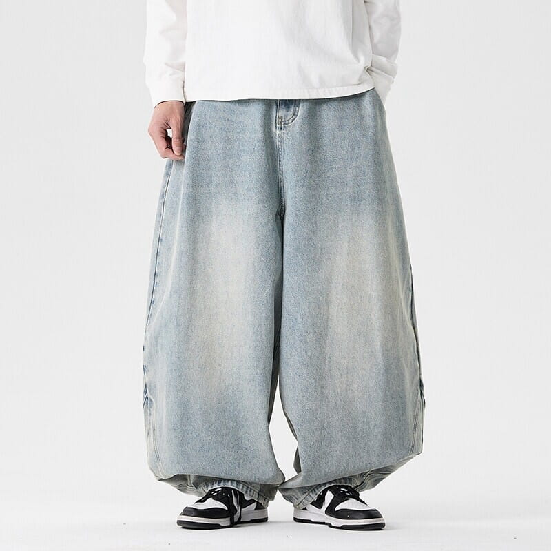 Des jeans japonais rétro à jambes larges pour hommes en grandes tailles en denim clair, avec une coupe ample et un aspect vieilli présentant des marques d’usure.