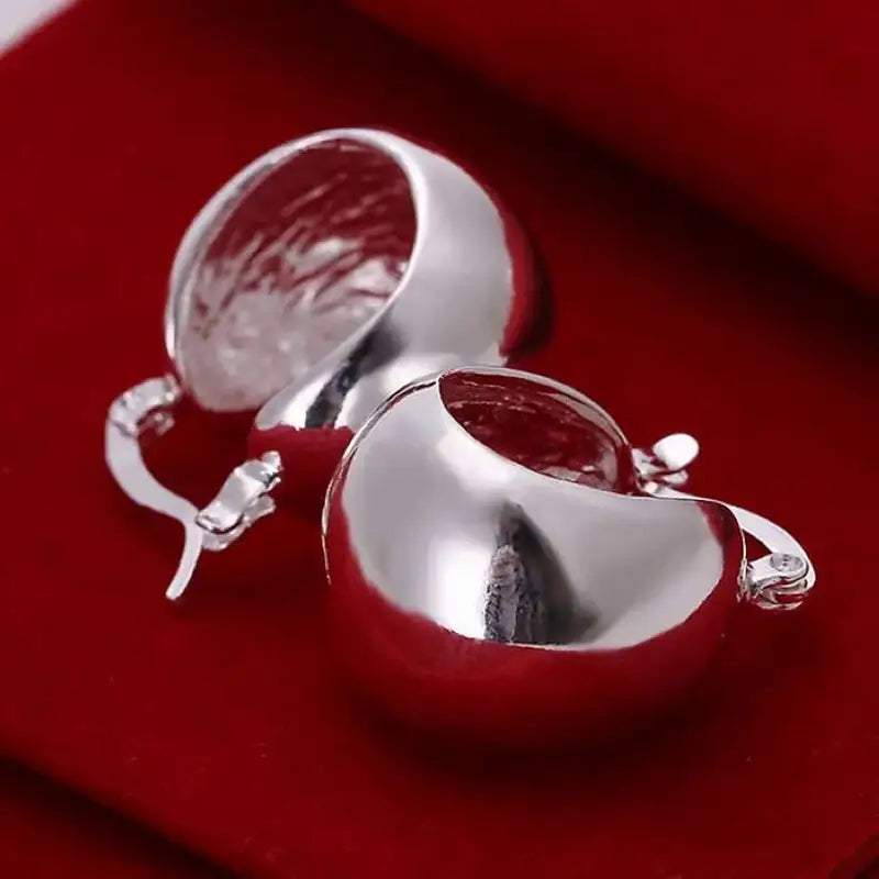 Boucles d’oreilles créoles minimalistes en argent sterling 925, en forme de poire argentée brillante, avec une finition métallique polie et de petites touches de cristal.