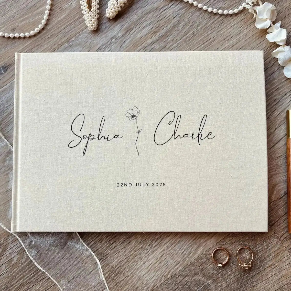 Album Polaroid de livre d’invités de mariage en lin beige personnalisé, recouvert de lin, présentant une écriture cursive noire et une délicate illustration florale entre les noms sophia et charlie, daté du 22 juillet 2025.