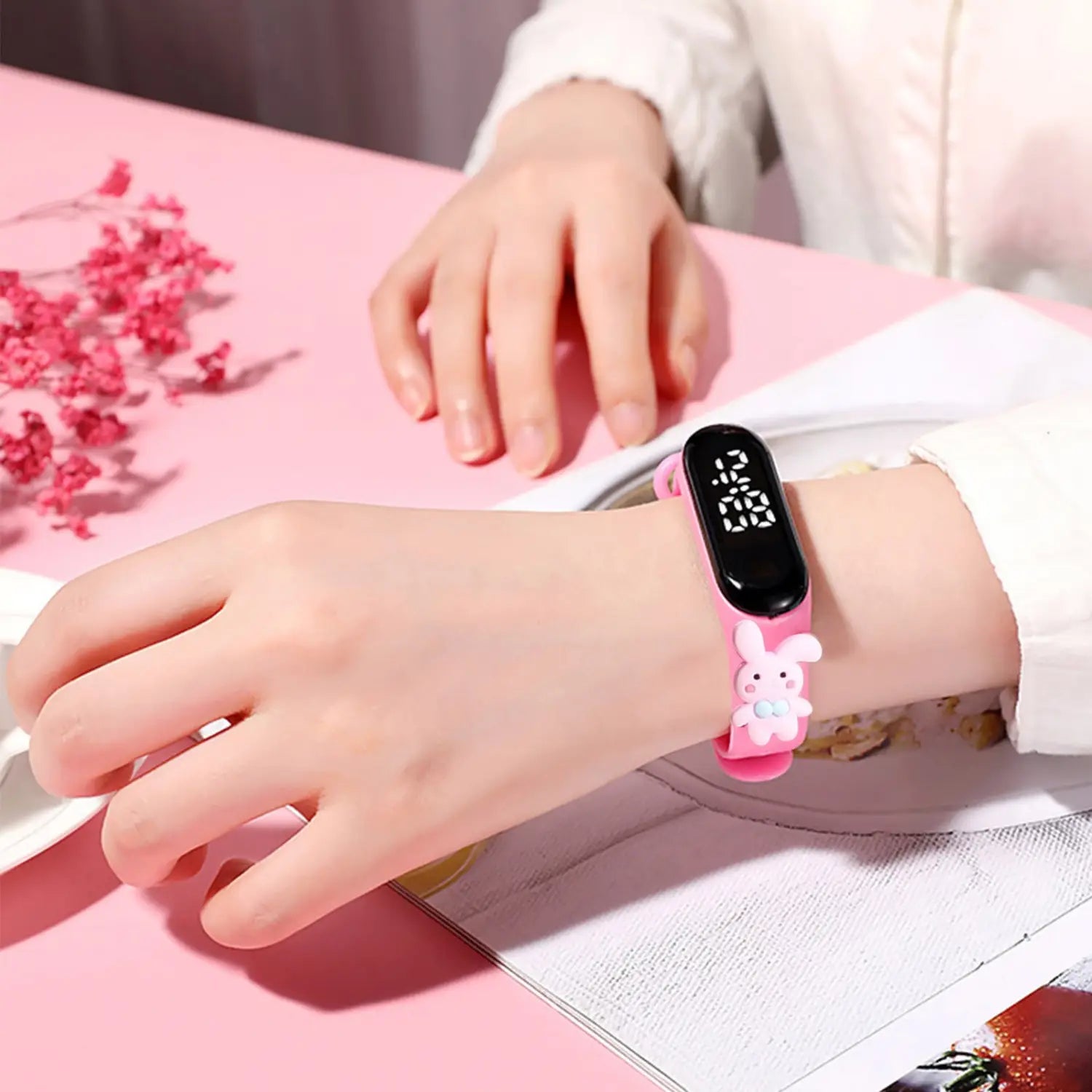 Pink silicone digital kids watch with life waterproof feature and a cute white bunny charm attached