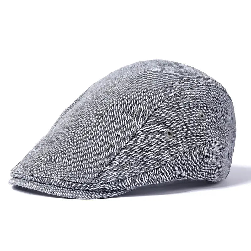 Denim-Flachmütze im Vintage-Béret-Stil, verstellbar, in grauer, strukturierter Beschaffenheit mit dezenter Ziernähung und zwei kleinen Knopfdetails.