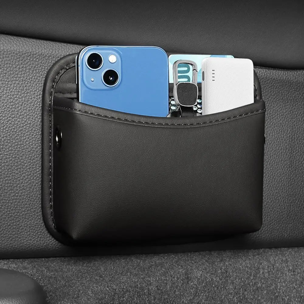 Pochette de rangement pour voiture en cuir noir avec adhésif en similicuir, organisateur contenant un téléphone bleu, des clés et une batterie externe.