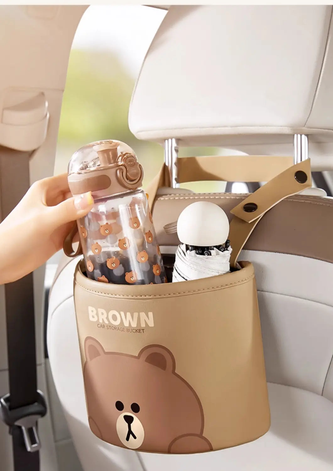 Cubo organizador de asiento trasero para coche de piel sintética marrón y beige, con rostro de osito de dibujos animados y marca en color marrón, diseñado para uso en el asiento trasero.