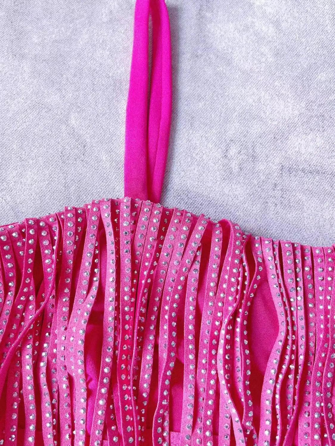 Haut rose fuchsia vif à franges, avec des détails en strass scintillants le long des bretelles et des franges, assorti à une mini-jupe taille haute à franges en strass.