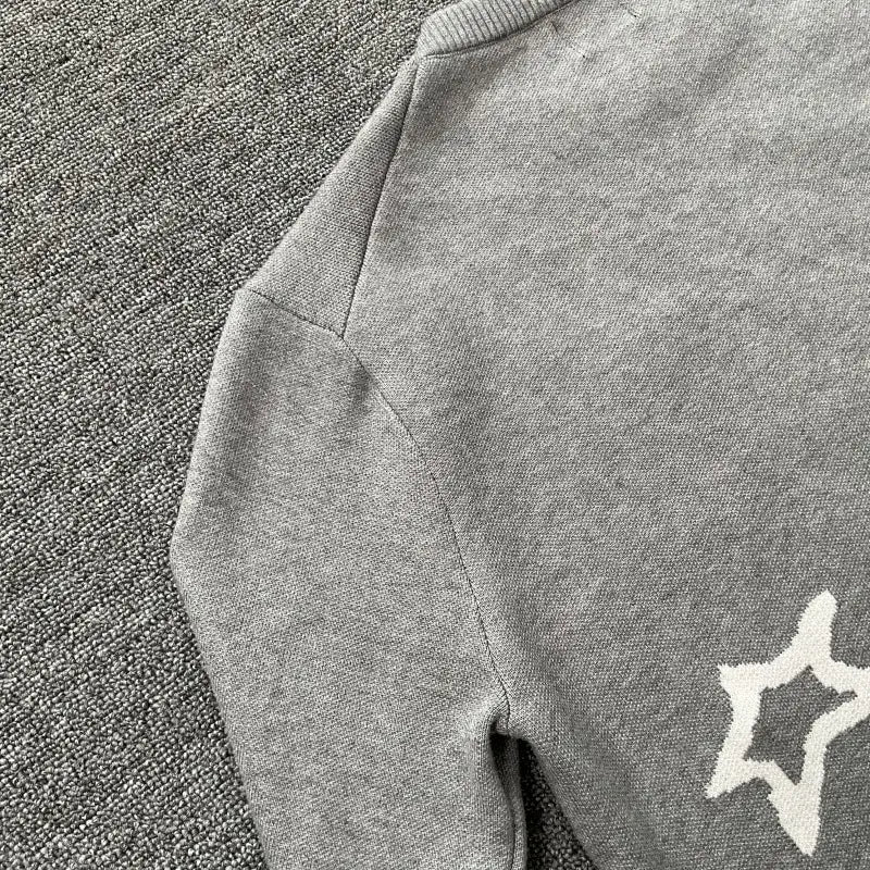 suéter de punto gris con una estrella bordada en blanco en la manga, de la colección de suéter de punto con bordados y gráfico