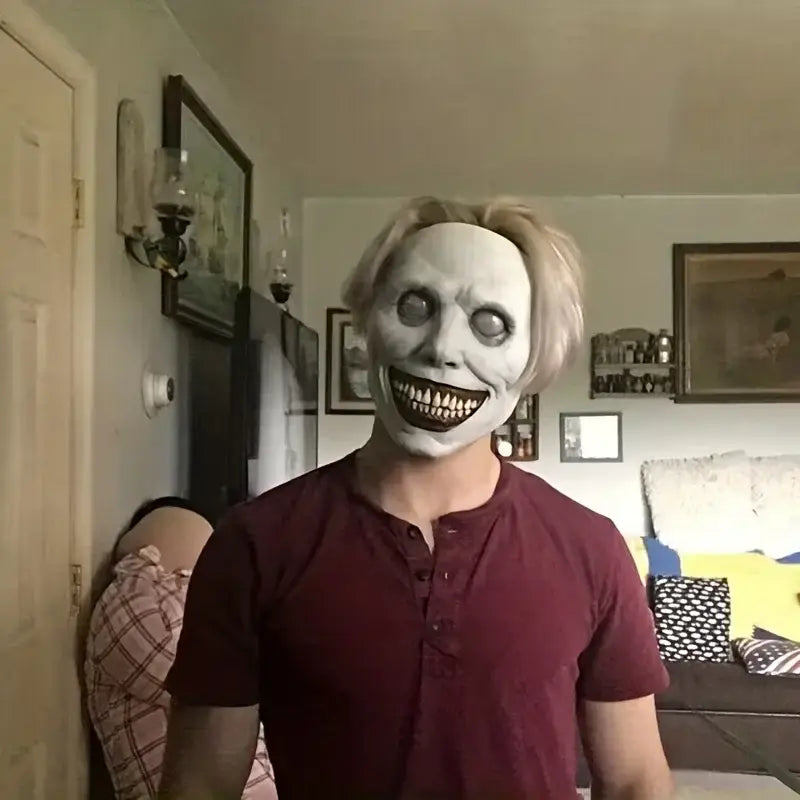White latex creepy halloween horror mask with blonde hair and exaggerated grin full face costume accessory made of resin.