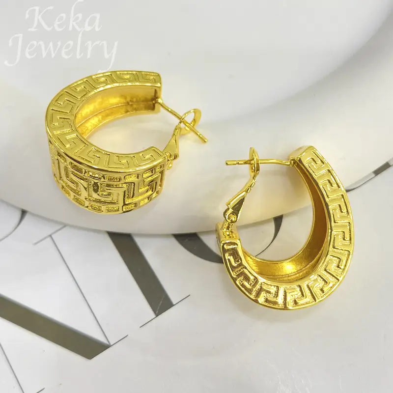 Goldfarbene Creolen mit einem kunstvollen griechischen Mäander-Design in einem Schmuckset mit griechischem Mäander, einschließlich Anhänger und Creolen.