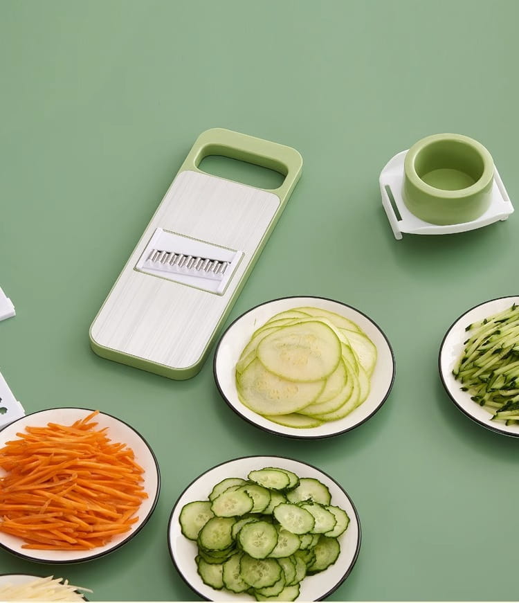 Light green and white multi-functional stainless steel vegetable slicer shredder with multiple blade attachments for julienning dicing and slicing vegetables.