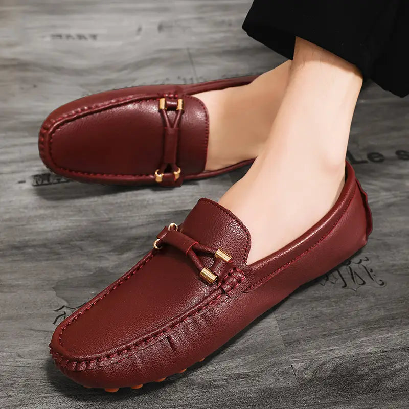Chaussures à enfiler habillées en cuir bordeaux pour hommes, avec un design à enfiler, des accents métalliques ton or et un style classique de mocassin pour un port décontracté.