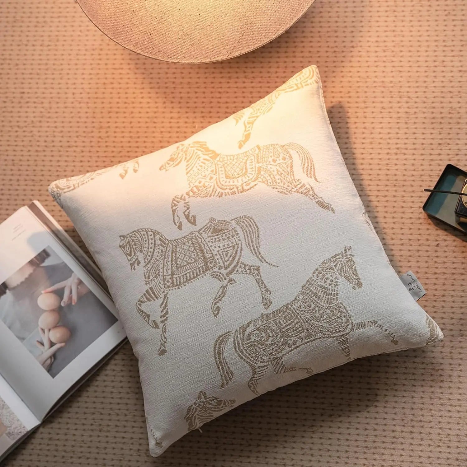 housse de coussin de luxe couleur lin sec présentant un tissu de couleur crème avec des motifs de chevaux brodés aux tons or complexes en motif en jacquard géométrique.
