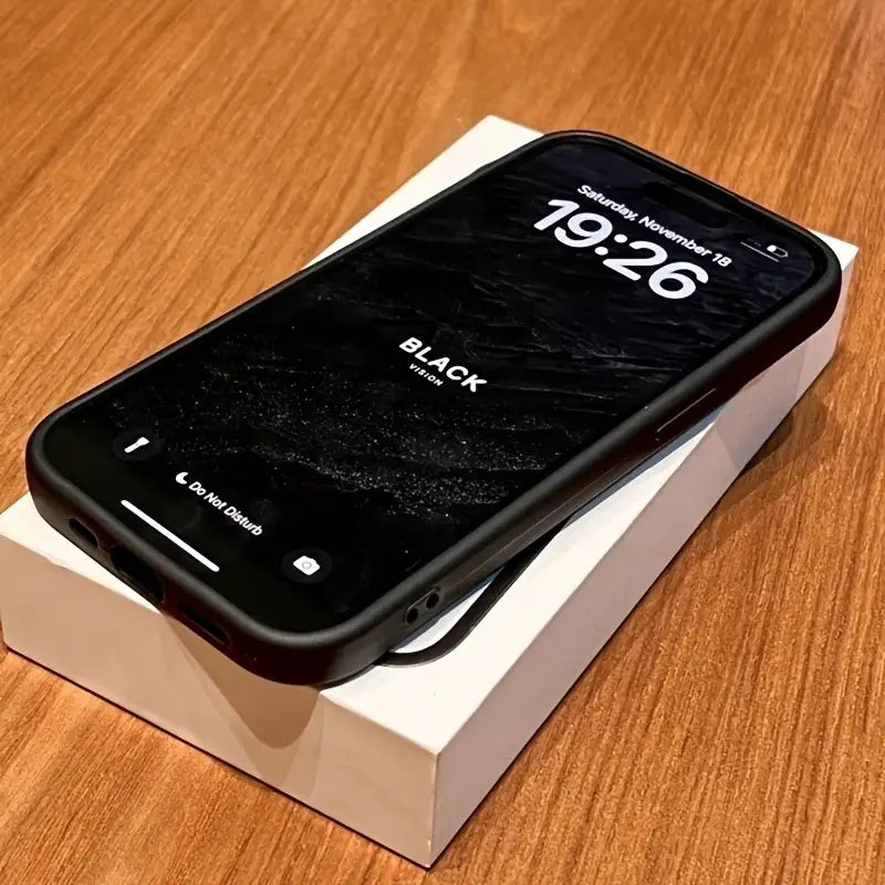 iPhone negro con estuche a prueba de golpes mate con mapa de brújula, apoyado sobre su caja minorista blanca, mostrado desde el reverso.