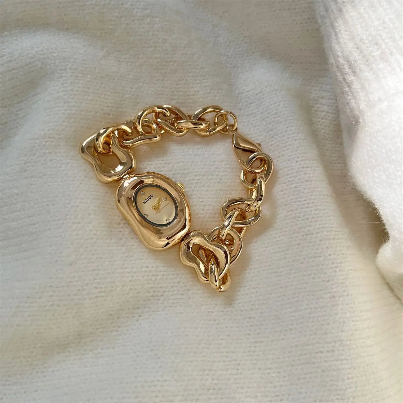 Gold chain link vintage wristwatch featuring a gold-toned chain-link bracelet and a sleek oval-shaped face with a polished metallic finish.