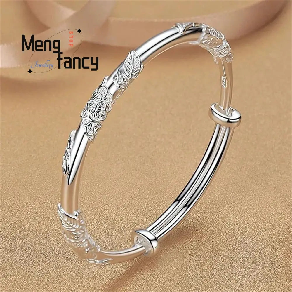 Silver floral-patterned bangle bracelet with intricate leaf and petal designs and a sleek adjustable clasp paired with natural jade raw stone for elegant sliding wear.