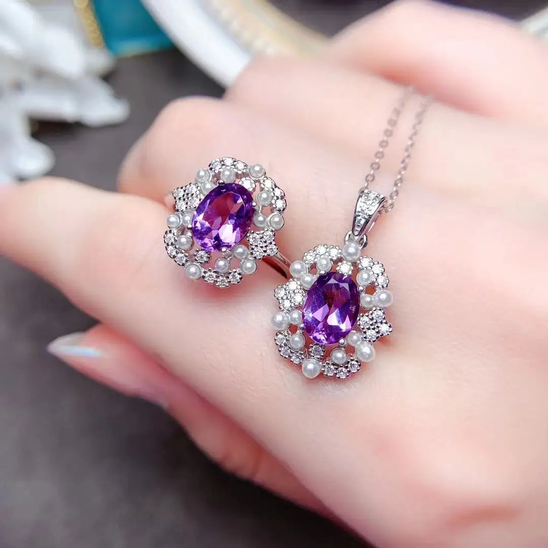 Un élégant ensemble comprenant un pendentif en améthyste violette et des boucles d’oreilles assorties, avec des pierres taillées en ovale, entourées de diamants étincelants et d’accents de perles, dans un écrin en argent sterling à tonalité argent, issu de l’ensemble de bijoux en argent sterling avec quartz rose.