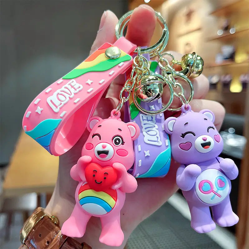 Pink and purple care bears silicone cartoon keychain backpack pendants each featuring rainbow details and holding a heart-shaped charm.