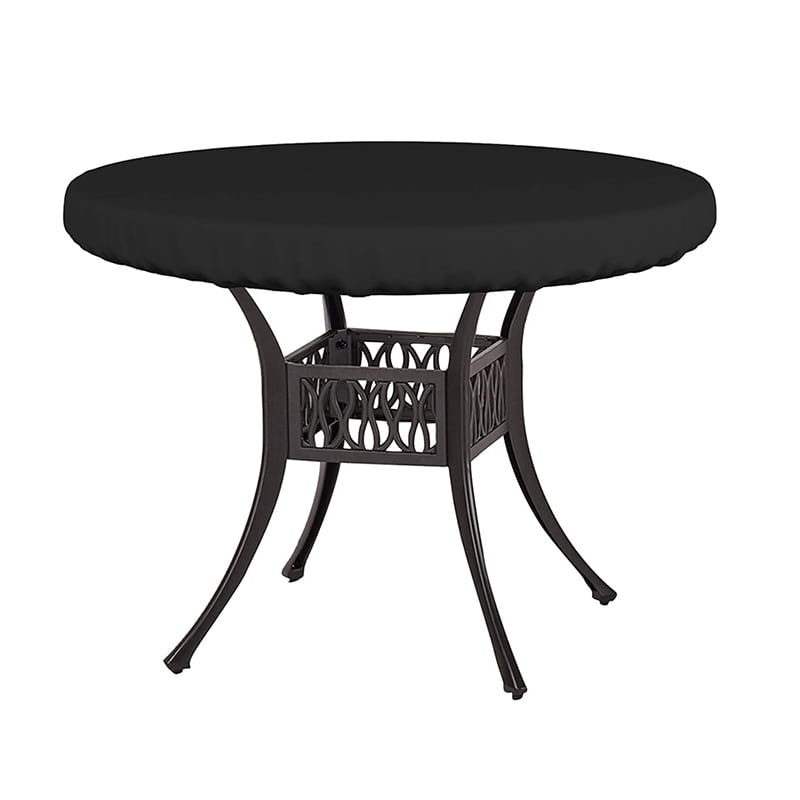 Mesa de comedor para exterior acolchada en negro, con estructura metálica oscura, patas curvadas ornamentales y base calada, bajo una funda redonda para mesa de jardín al aire libre impermeable.
