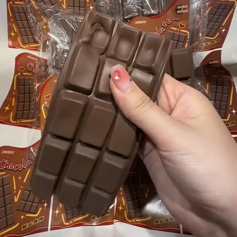 A chocolate bar squeeze toy made of smooth glossy brown material with molded segments resembling real chocolate designed as a slow rising sensory fidget.