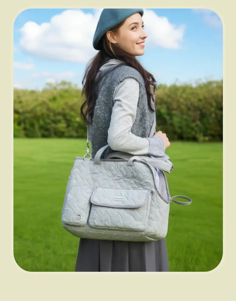 Bolsa transportín acolchada de color gris claro para mascotas, con bolsillo frontal y correa de hombro ajustable, diseñada para gatos y perros pequeños.