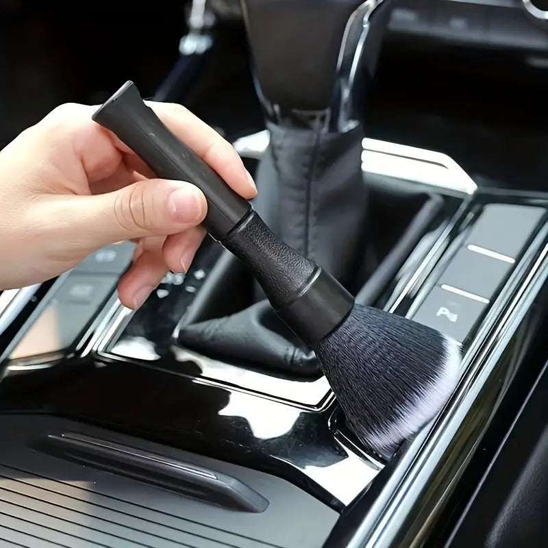 Bürste zur Detailreinigung im Innenraum eines schwarzen Fahrzeugs mit weichen Borsten, strukturierter Griffausführung und dichten weichen Borsten für eine effektive Reinigung.