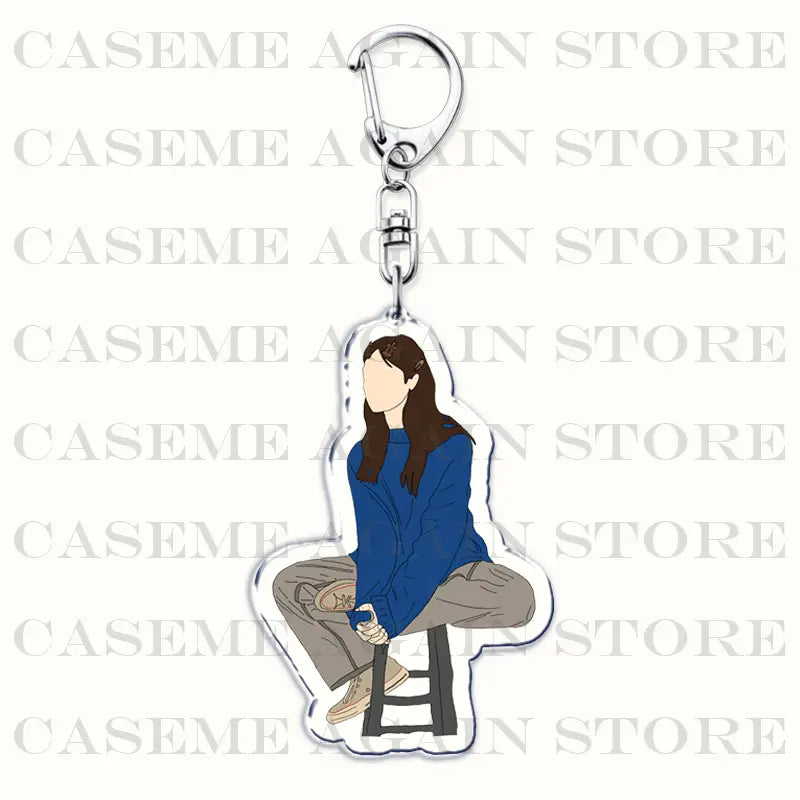 Clear acrylic keychain featuring a stylized illustration of a person with long brown hair wearing a blue sweater and beige pants seated on a stool from the Gracie Abrams acrylic keychain anime fan gift.