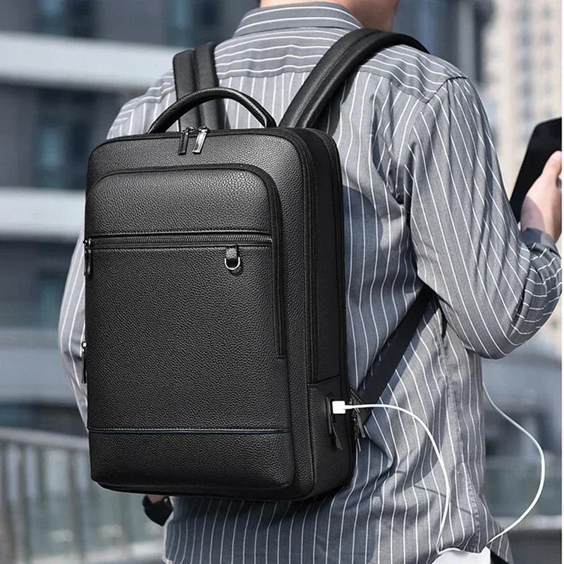 sac à dos pour ordinateur portable en cuir noir texturé avec plusieurs fermetures éclair et port latéral de charge USB, conçu comme un sac d’affaires pour transporter des ordinateurs portables.