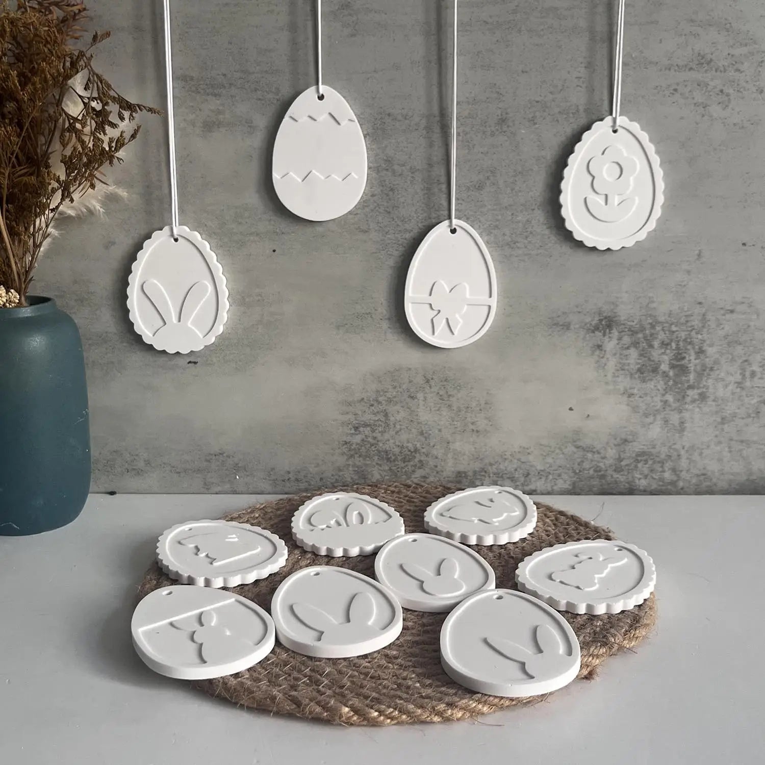 white ceramic Easter egg ornaments with embossed designs arranged on a surface showcasing the Easter Bunny silicone resin pendant mold product.