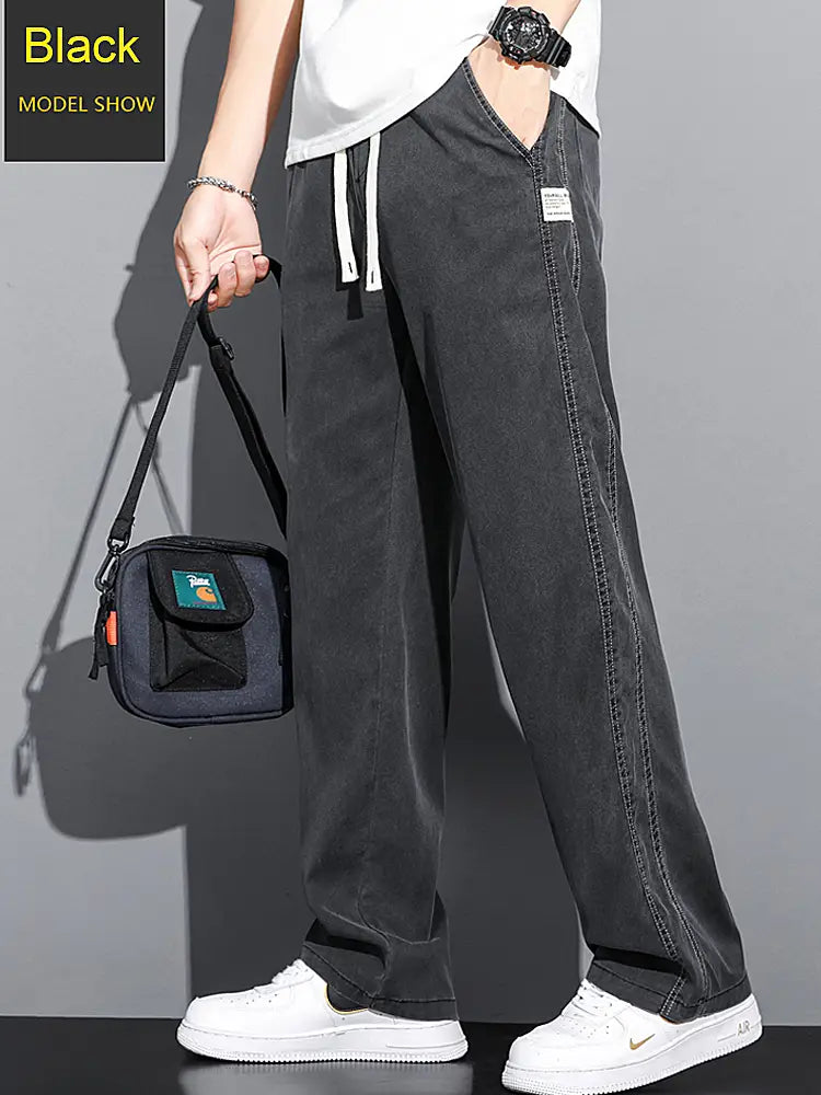 men’s lyocell casual loose straight black denim joggers with white drawstrings and a small patch on the side seam.