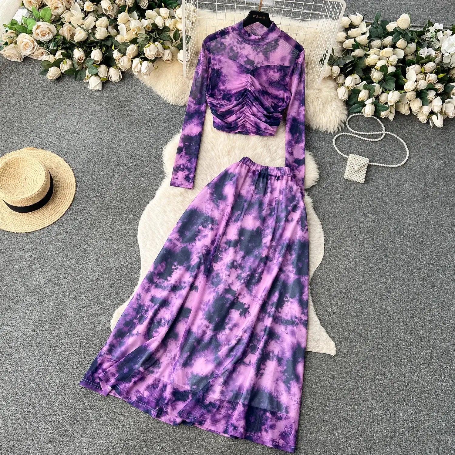 Purple and navy tie-dye two-piece mesh skirt set with a ruched long-sleeve top and flowing maxi skirt featuring an elastic closure type.