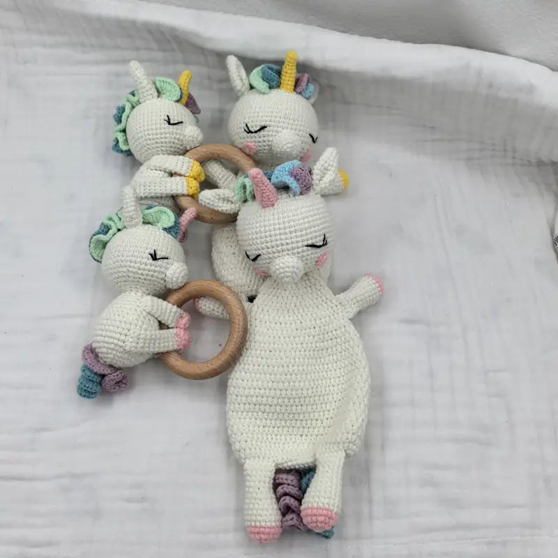 Gehäkelte weiße Einhorn-Baby-Schmusedecke-Sicherheitsdecke mit Rassel sowie Akzenten für Mähne, Horn und Schwanz in Regenbogenfarben.