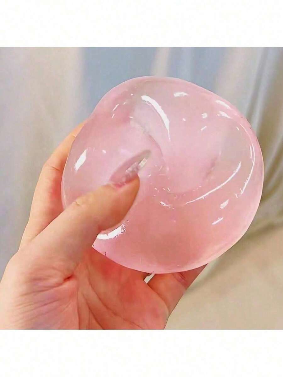 Une balle compressible antistress translucide rose, gélatineuse, avec une surface lisse légèrement brillante, issue de la gamme de produits Blue Coconut Oil.