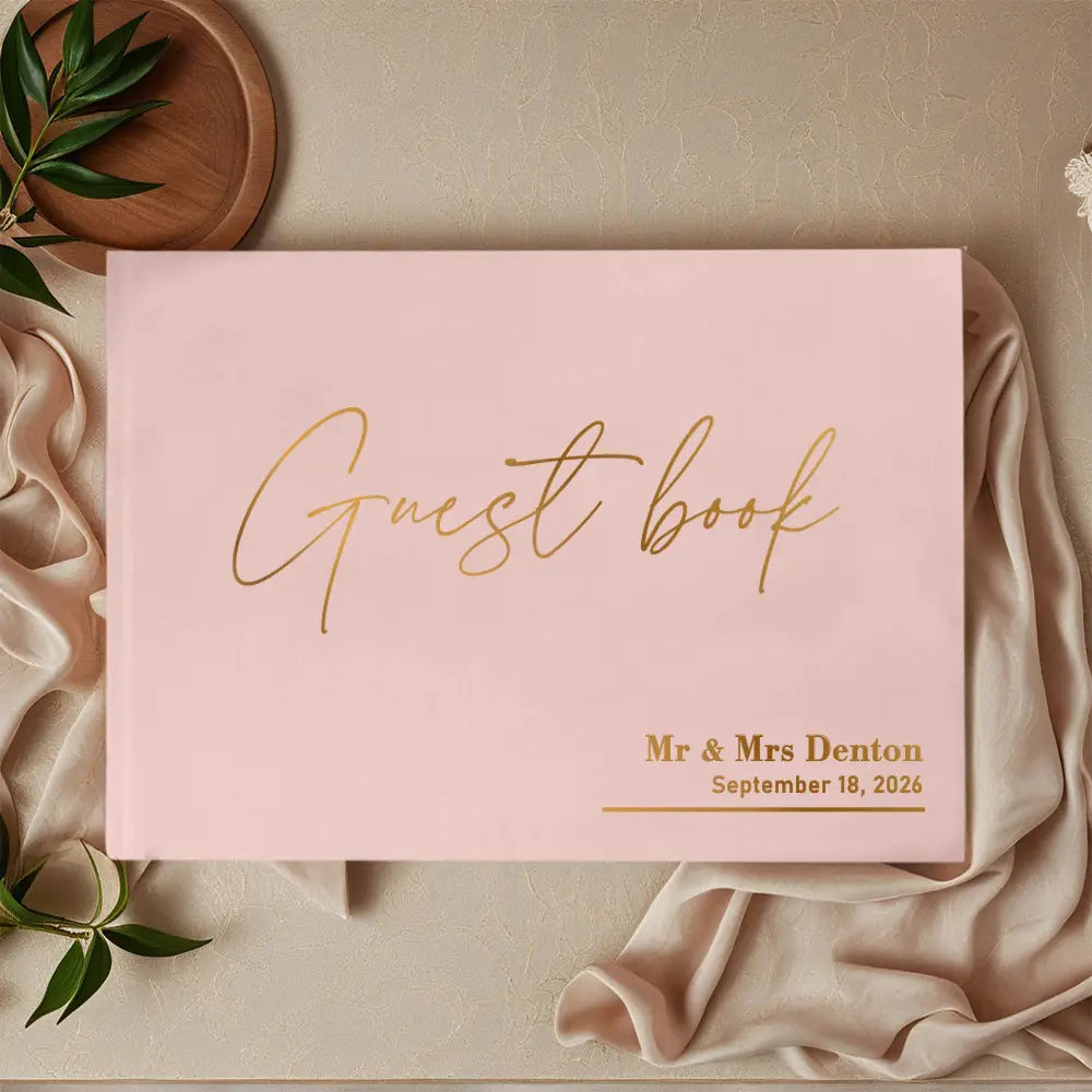 personalized pink wedding guest book with pen featuring gold foil lettering and a customized engraving on the cover.