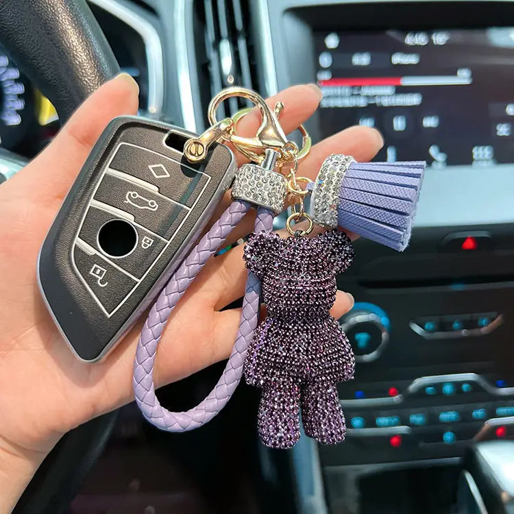 Rhinestone bear keychain featuring a purple crystal-encrusted teddy bear with a braided lavender leather strap and matching tassel.